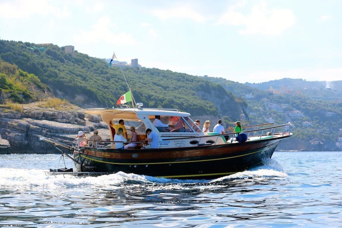Boat cruising with tourists on a sunny day. Naples Italy coastline.
